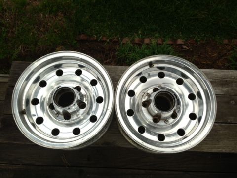 1986 Ford Bronco - Two aluminum wheels with a 5x5.5 bolt pattern are displayed on a wooden surface.
