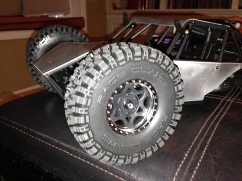 1986 Ford Bronco - RC rock crawler with "Race Claws" tires and a silver body sits on a dark surface.