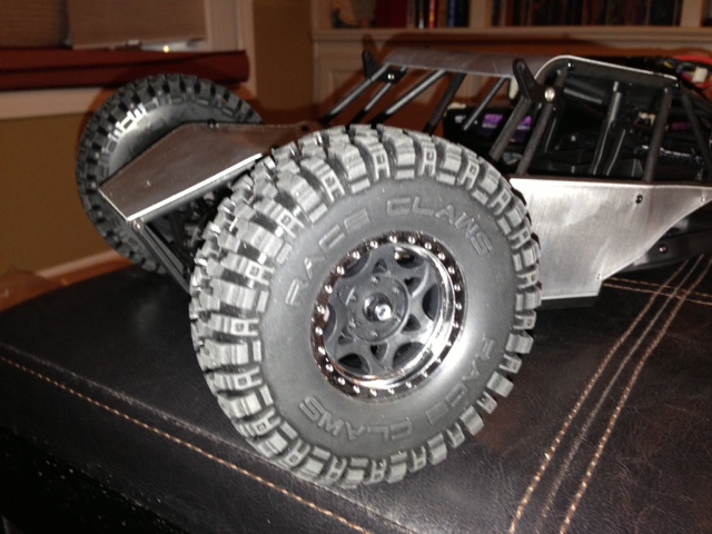 Close-up of a remote control rock crawler's large knobby tire and metal body panels
