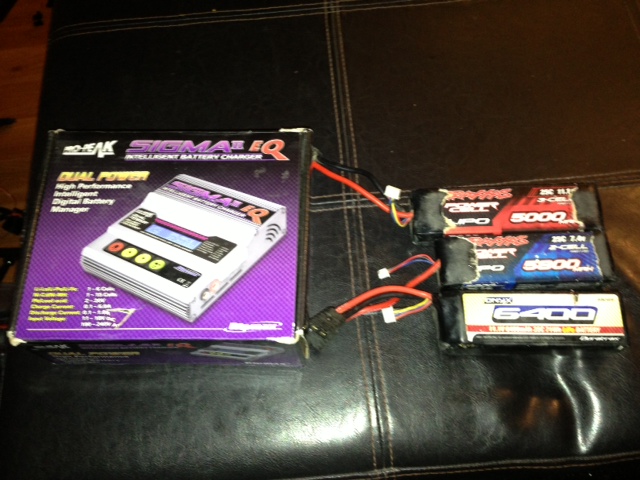 Boxed dual power intelligent battery charger next to three RC LiPo batteries