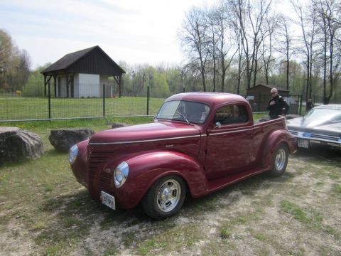1991 Ford LTD Crown Victoria - A classic maroon 1940 Ford pickup truck is parked outdoors next to another vehicle.