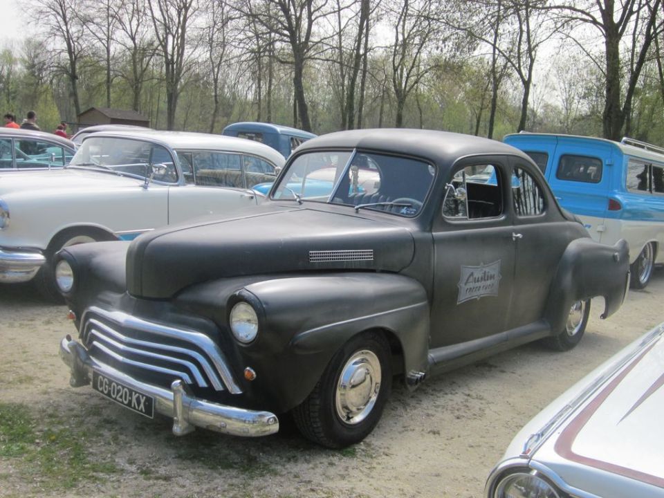 Dark coupe parked next to other cars, with lettering on the door