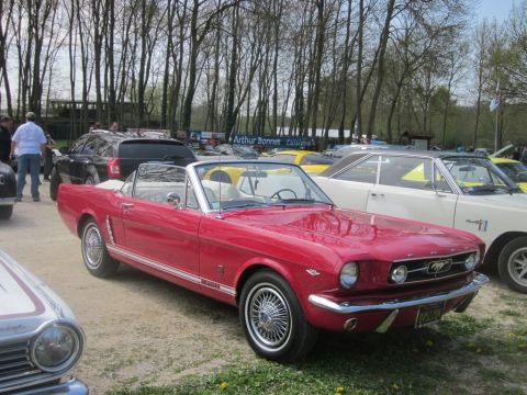 1991 Ford LTD Crown Victoria - A classic red Ford Mustang convertible is parked at an outdoor event with other vehicles.