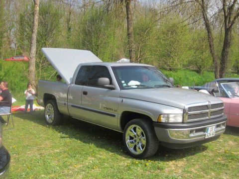 1991 Ford LTD Crown Victoria - This silver Dodge Ram pickup truck features an open bed cover and chrome wheels. A pink convertible is visible in the background.