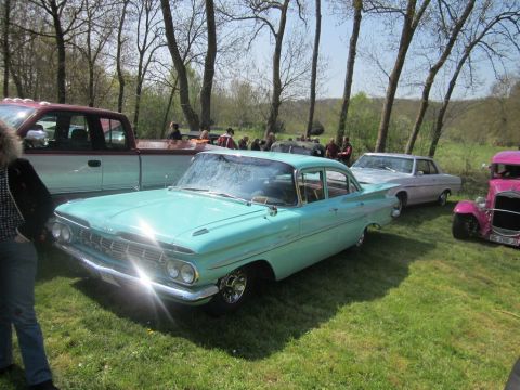 1991 Ford LTD Crown Victoria - A turquoise 1959 Chevrolet Bel Air is parked alongside other vehicles at an outdoor gathering.