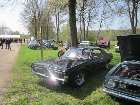 1991 Ford LTD Crown Victoria - A classic black Mercury Cougar is displayed at a car show alongside other vehicles and attendees.