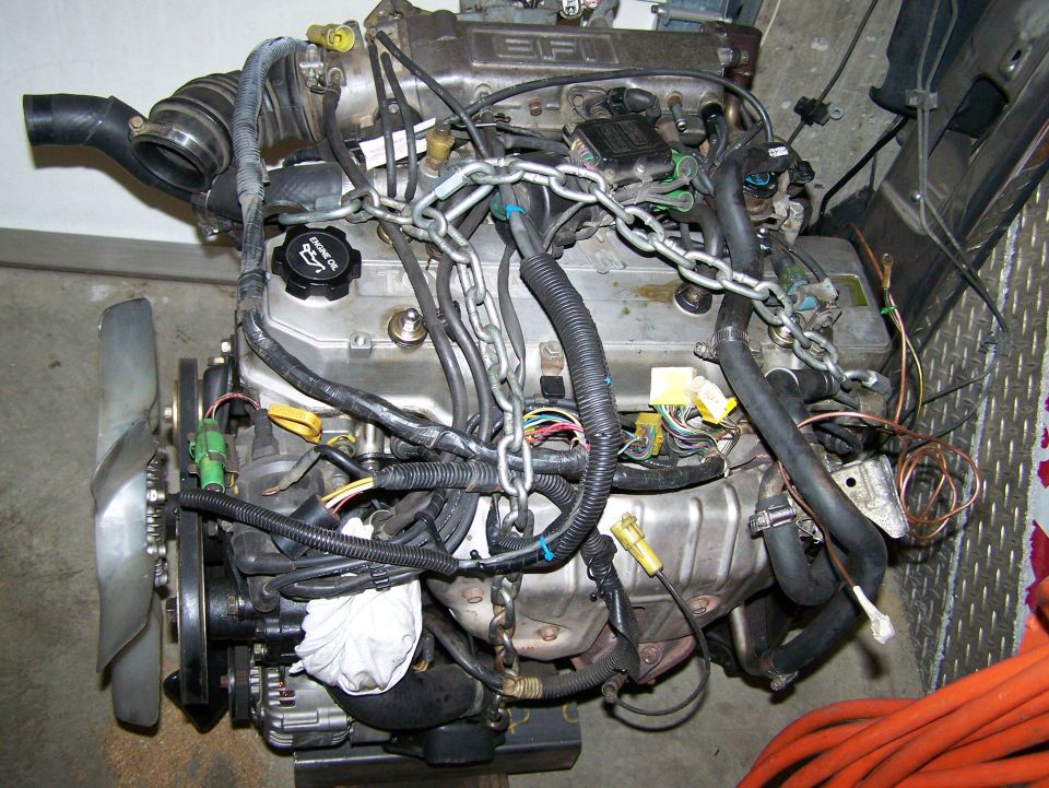 Engine with chains attached, fan on the left, lots of wires and hoses