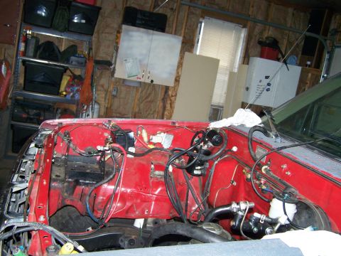 1988 Suzuki Samurai - The engine bay of a vehicle, showing various mechanical parts and wiring, possibly undergoing modification.