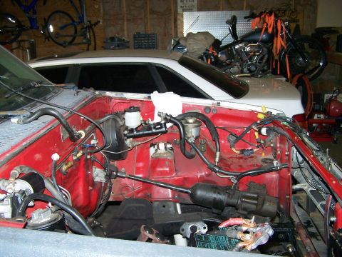 1988 Suzuki Samurai - The engine bay of a vehicle, showing the brake booster, master cylinder, and various hoses and wiring.