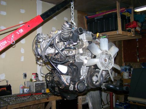 1988 Suzuki Samurai - Engine assembly being lifted by a hoist in a garage setting.