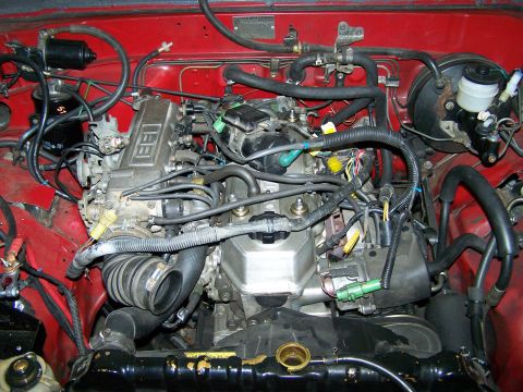 1988 Suzuki Samurai - The engine bay is filled with hoses, wires, and engine components. Text on the engine reads "EFI".