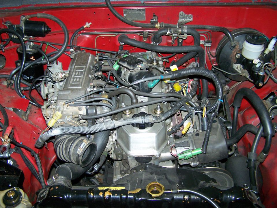 Engine bay with lots of hoses and wires. Has "EFI" on the engine cover