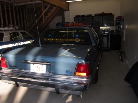 1991 Ford LTD Crown Victoria - A light blue police car is parked in a garage, with another police car visible to the left.