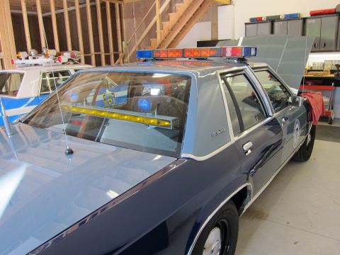 1991 Ford LTD Crown Victoria - Rear view of a 1991 Ford Crown Victoria LTD police car with its hood open, parked indoors.