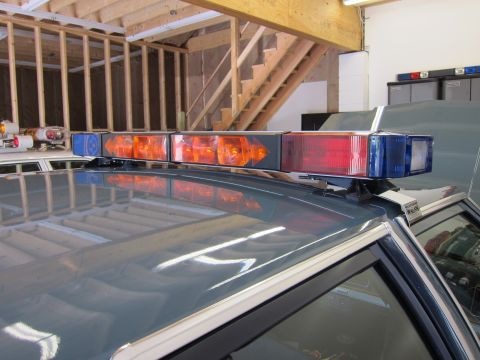 1991 Ford LTD Crown Victoria - A 1991 Ford Crown Victoria LTD police car is parked inside a garage, equipped with a light bar on its roof.