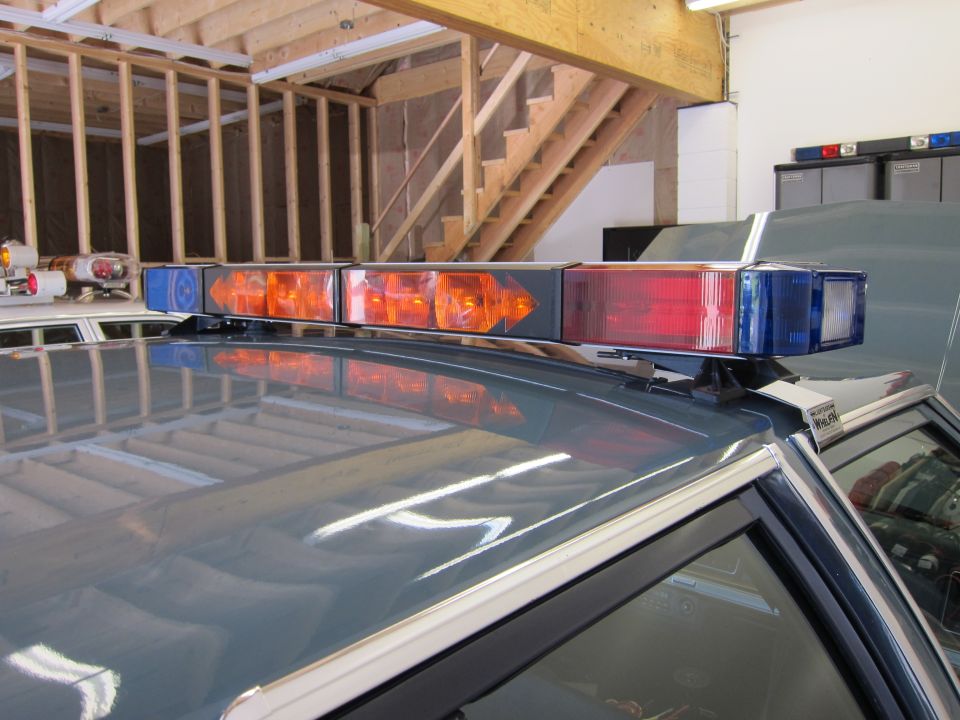 Gray 1991 Ford Crown Victoria LTD police car roof with light bar, showing reflection of garage interior