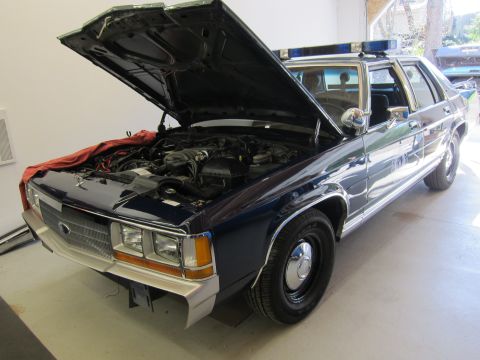 1991 Ford LTD Crown Victoria - A 1991 Ford Crown Victoria LTD police car is shown with its hood open, revealing the engine compartment.