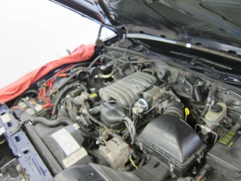 1991 Ford LTD Crown Victoria - The engine bay of a vehicle, with a red cloth covering part of the fender and engine components visible.
