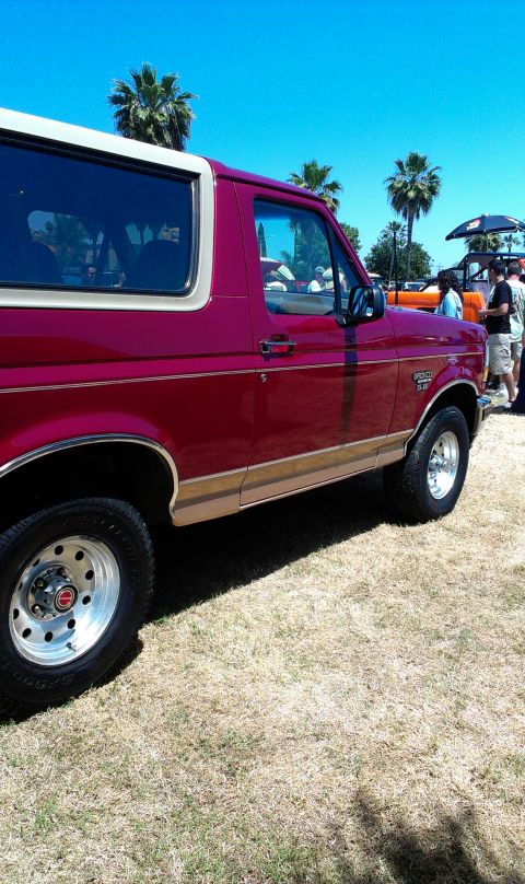 1994 Ford Bronco - Side view of a red Ford Bronco, likely from the early to mid-1990s, with tan accent trim.