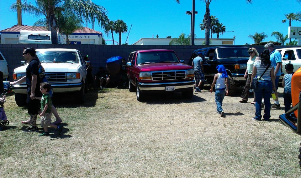 Maroon Ford Bronco parked outside with people around