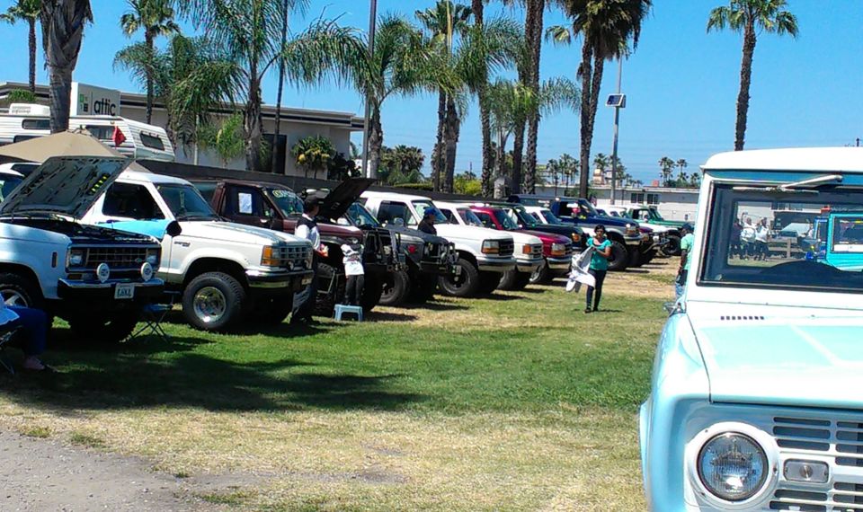 Light blue and white 1992 Ford Bronco front view, parked on grass with other vehicles