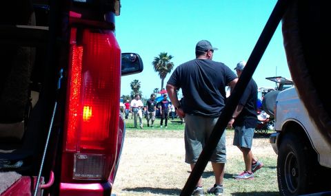 1994 Ford Bronco - View of a red SUV's rear, with people gathered in a field under a clear blue sky.