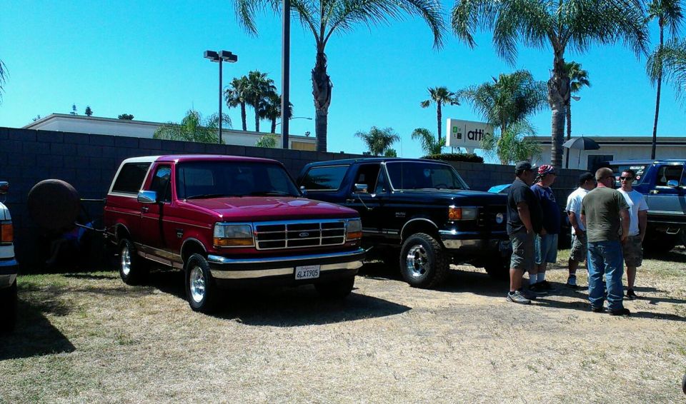 Red 1994 Ford Bronco parked next to a black Bronco