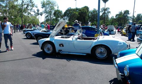 1994 Ford Bronco - A white convertible sports car is displayed at an outdoor car show with its hood open.
