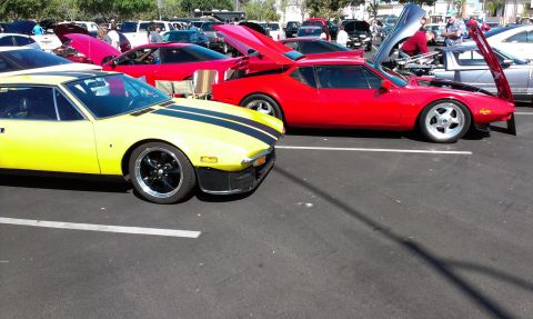 1994 Ford Bronco - Two sports cars are parked in a lot, one yellow and one red, with several other vehicles in the background.