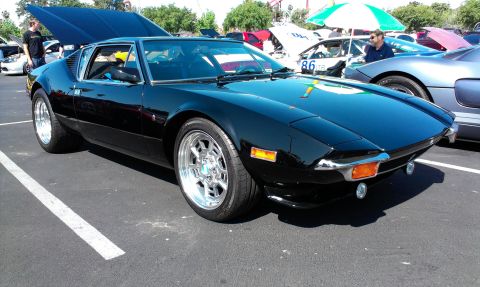 1994 Ford Bronco - A black De Tomaso Pantera is parked at an outdoor car show with its hood open.