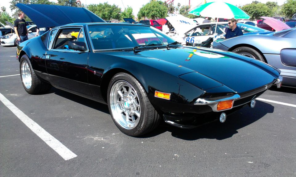 Black De Tomaso Pantera with hood up, parked at an outdoor event