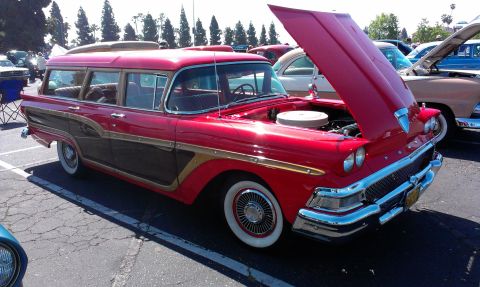 1994 Ford Bronco - A classic red station wagon with wood paneling is displayed at a car show, its hood open.