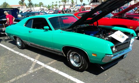 1994 Ford Bronco - A turquoise 1970 Ford Torino GT is displayed at a car show with its hood open, revealing the engine.