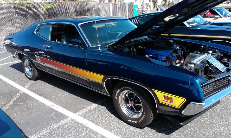Dark blue Ford Gran Torino Sport with yellow and red side stripes, hood open showing engine