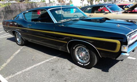 1994 Ford Bronco - A black 1970 Ford Torino GT coupe is parked next to another car, showing its side profile and front end.