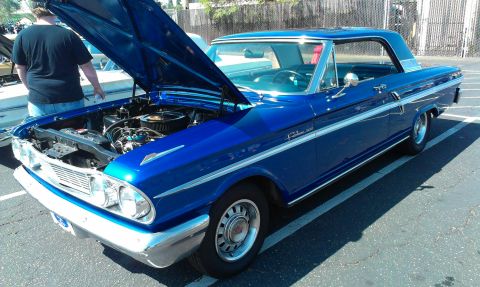 1994 Ford Bronco - A blue 1962 Ford Fairlane 500 coupe is parked with its hood open, revealing the engine bay.