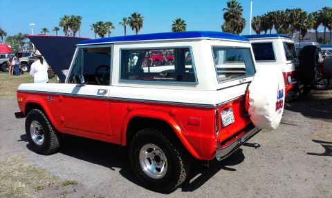 1994 Ford Bronco - A classic two-tone Ford Bronco is parked outdoors with palm trees in the background.