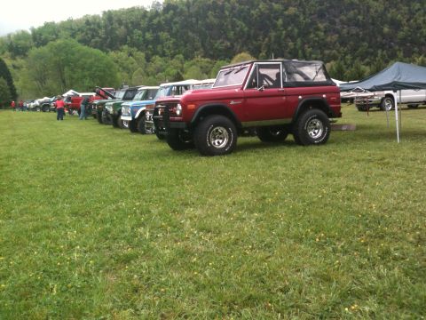 1992 Ford Bronco - Several Ford Broncos are lined up on a grassy field during an event.