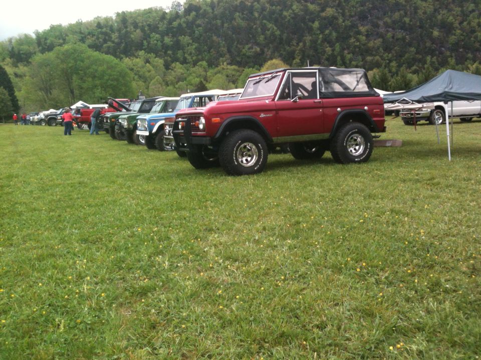 Red 1978 Ford Bronco parked in a line with other Broncos on a grassy field