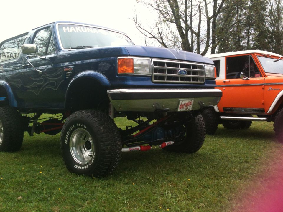 Blue 1992 Ford Bronco with flame decals, lifted, in a 3q-front view