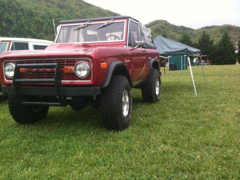 1992 Ford Bronco - First-generation Ford Bronco with a bull bar and aftermarket wheels sits on a grassy field.