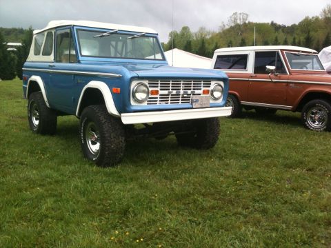 1992 Ford Bronco - A blue 1973 Ford Bronco is parked on a grassy field next to another Bronco.