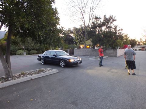 2003 Ford Crown Victoria - Black Crown Victoria on multi-spoke wheels rolls through a residential driveway while men look on