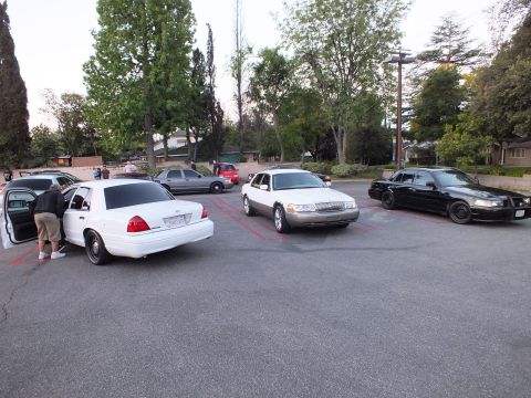2003 Ford Crown Victoria - Three Panther-platform sedans in white, silver and black sit parked side by side in a lot