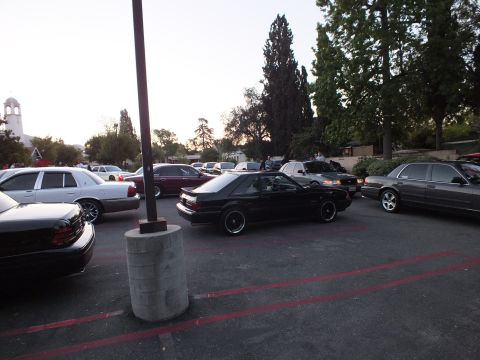 2003 Ford Crown Victoria - Lowered black hatchback parked among Mercury and Ford sedans in a lot near a church