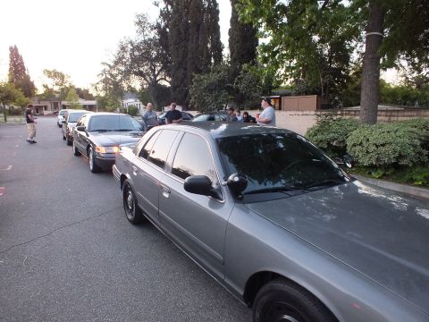 2003 Ford Crown Victoria - Gray Crown Victoria parked curbside with a line of sedans and a small crowd at dusk