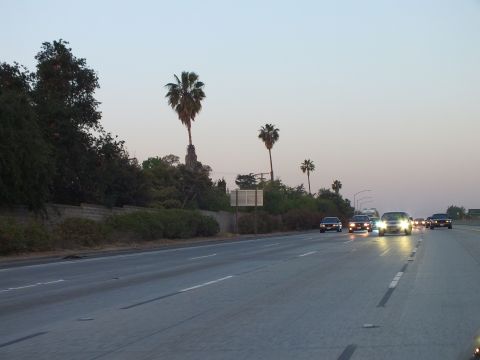 2003 Ford Crown Victoria - Wide freeway view at dusk with a small car pack approaching beneath palm trees