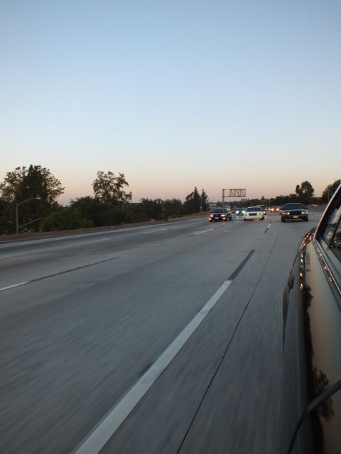 2003 Ford Crown Victoria - Dusk highway scene captured from a car window, traffic and a sign bridge in the distance.
