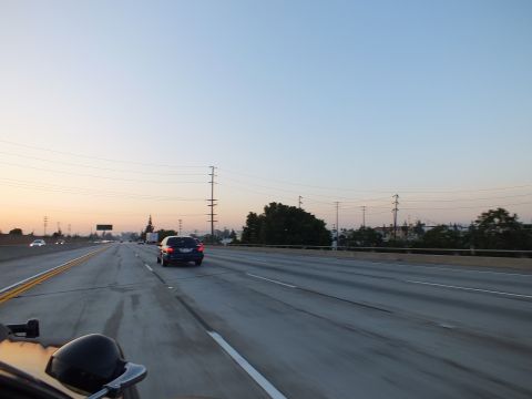 2003 Ford Crown Victoria - Twilight freeway with a dark blue sedan in the center lane and electrical pylons lining the right shoulder.