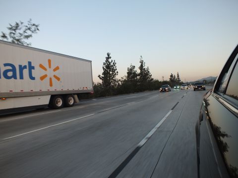 2003 Ford Crown Victoria - White Walmart tractor-trailer travels the adjacent lane at twilight as a dark car rides at frame right.
